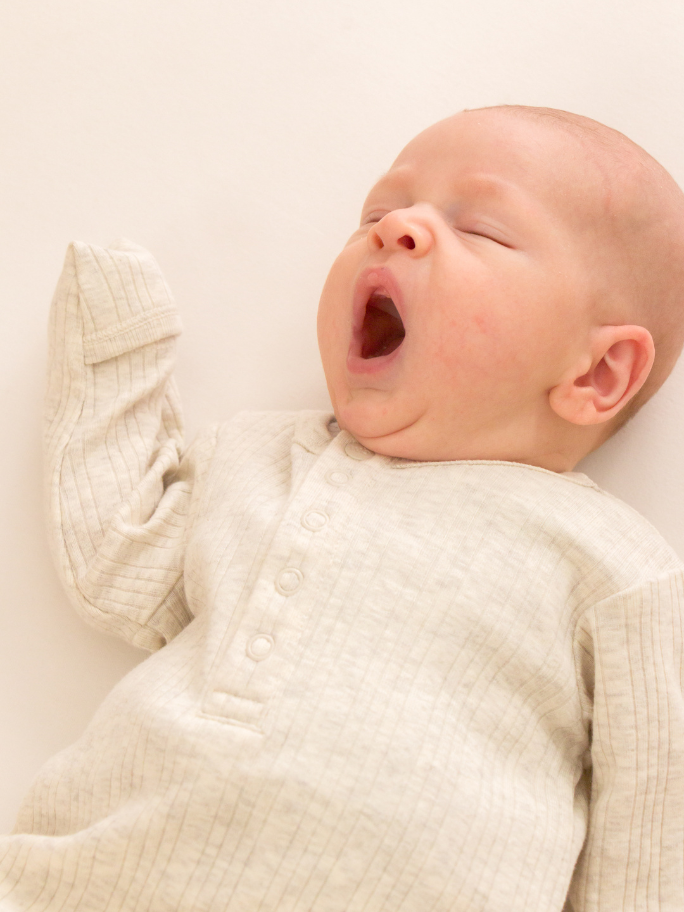 Baby yawning, wearing a ribbed baby gown