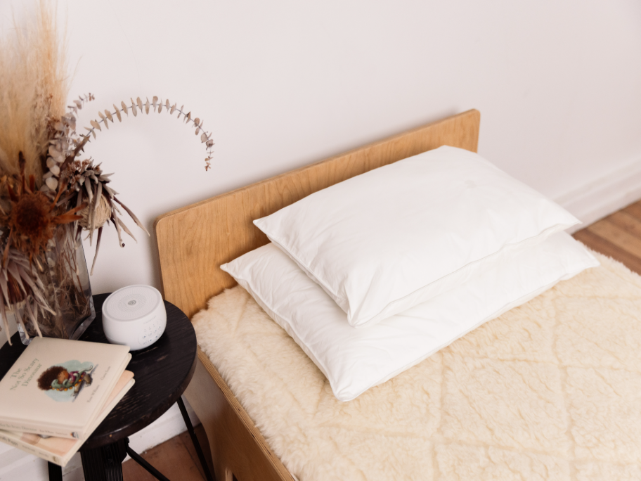 Single bed with woolen underlay and two white pillows at headboard