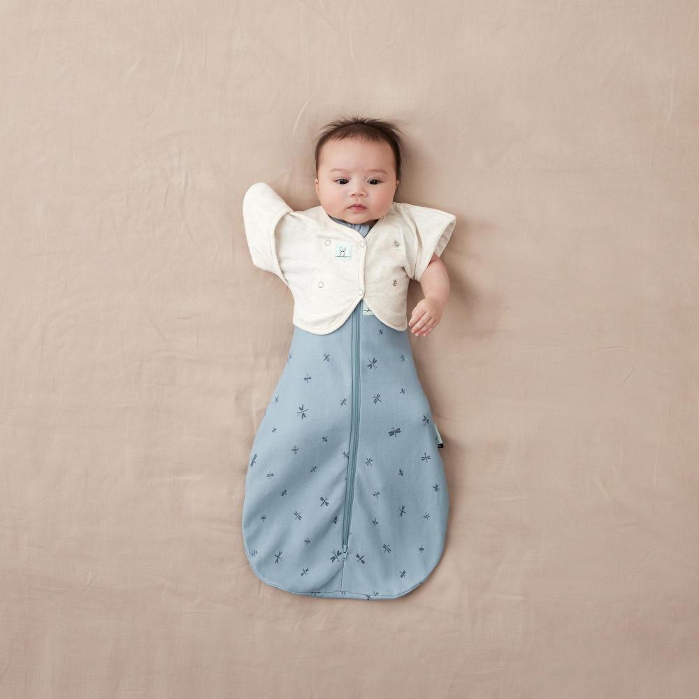 Baby wearing ergopouch swaddle and white arm warmer cardigan
