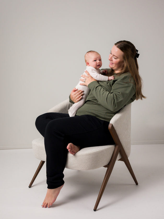 Mum holding baby wearing merino in a studio setting