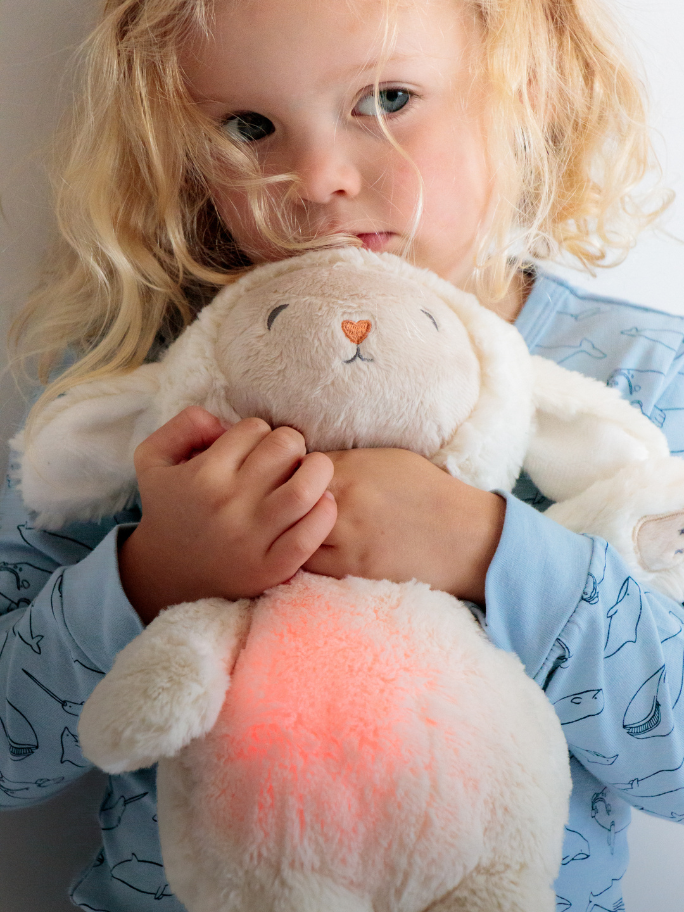 Close up of a toddler cuddling a cream coloured lou lou lamb