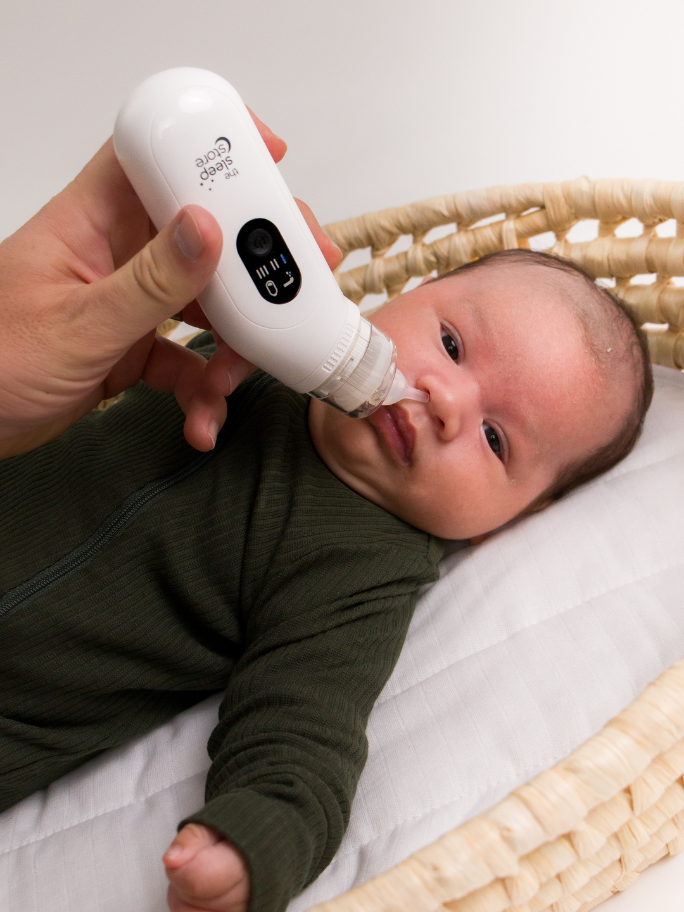 Baby in basket with nasal aspriator near his nose