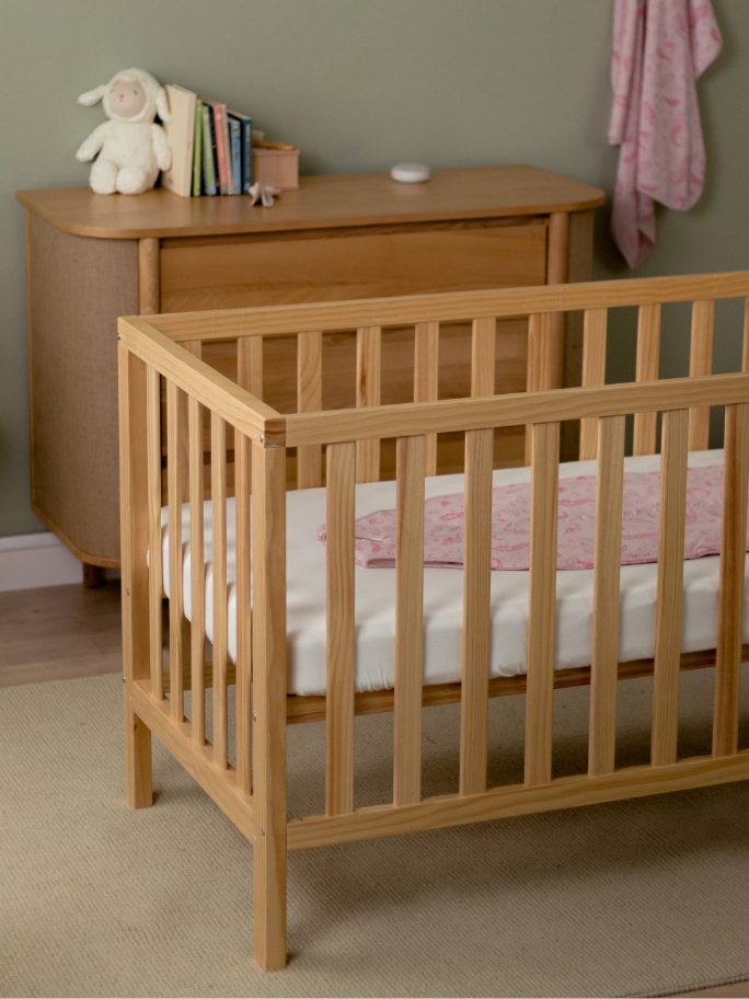 Bedroom setting with cot, dresser and soft furnishings