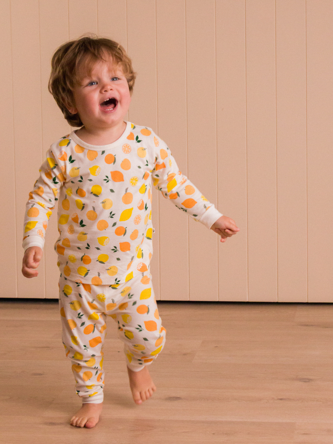 Toddler in citrus cotton pyjamas running in a studio setting