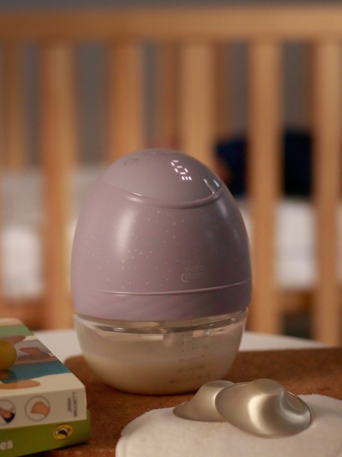 Purple wearable breastpump on bedside table with silver nipple cups in front