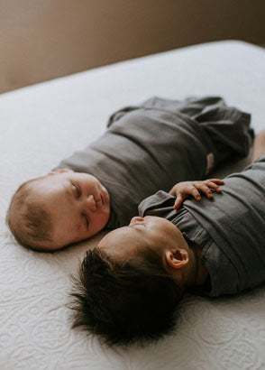 Babys looking at each other while wearing Embe swaddles