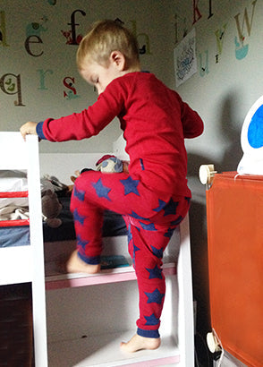 Boy climbing bunk bed steps in red pyjamas