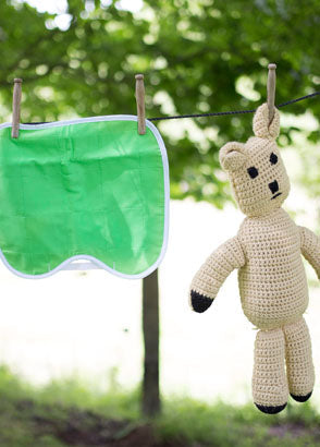 Brolly sheet car seat protector hung to dry beside knitted teddy