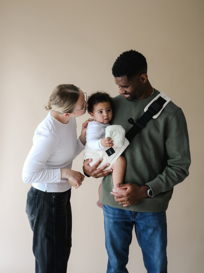 Parents with baby in carrier in studio setting