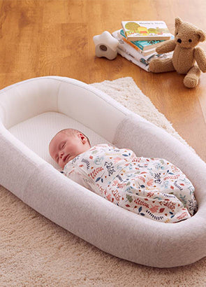 Newborn baby swaddled and sleeping in a Purflo sleep tight baby bed grey