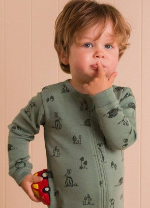 Toddler boy wearing a sage green merino zipsuit with woodland print