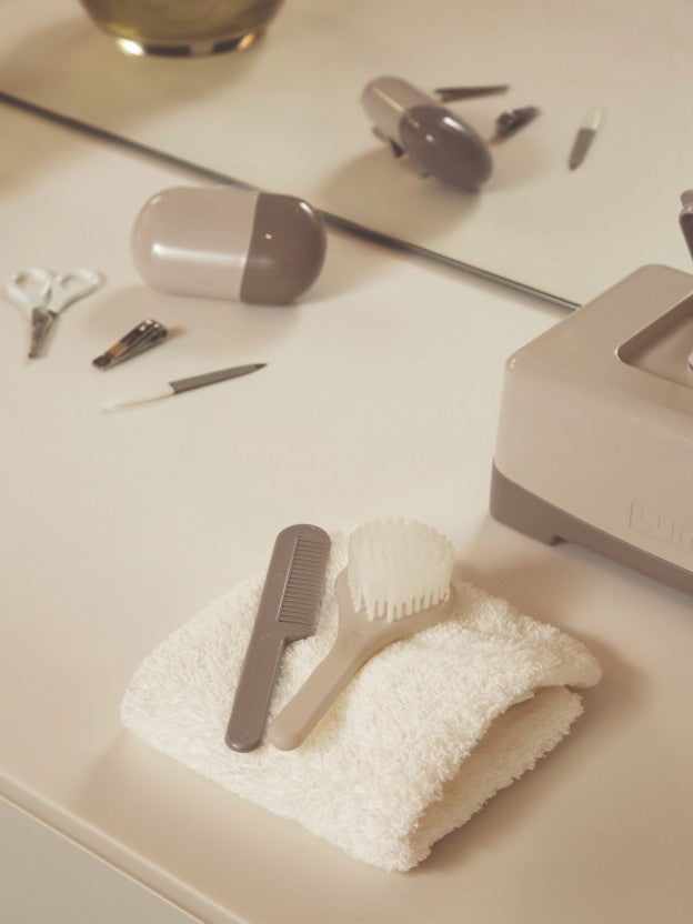 Baby care essentials including comb, brush and thermometer on a table