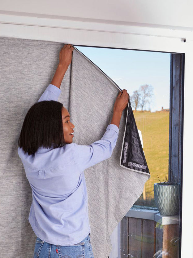 Woman hanging portable blackout blind on window