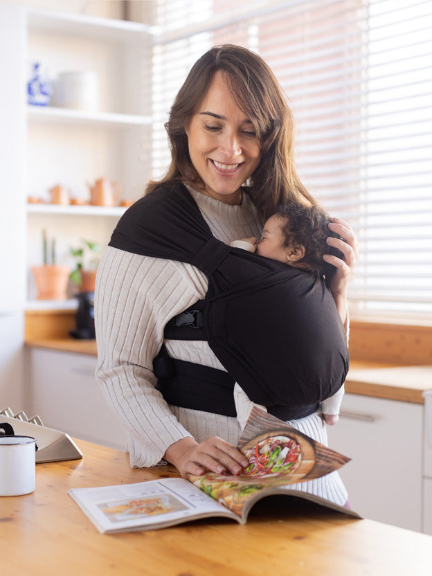 Mum wearing newborn in a black boba bliss hybrid baby carrier