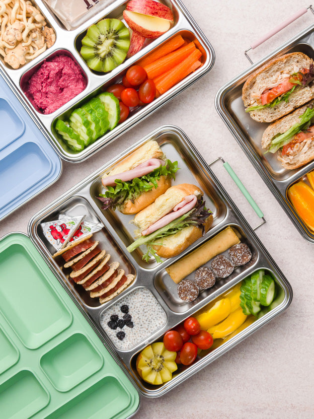 Stainless steel lunchboxes filled with colouful fruit, vegetables and filled rolls
