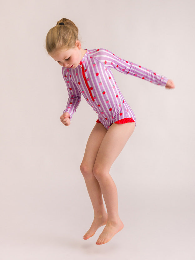Girl jumping wearing a long sleeve purple swim suit