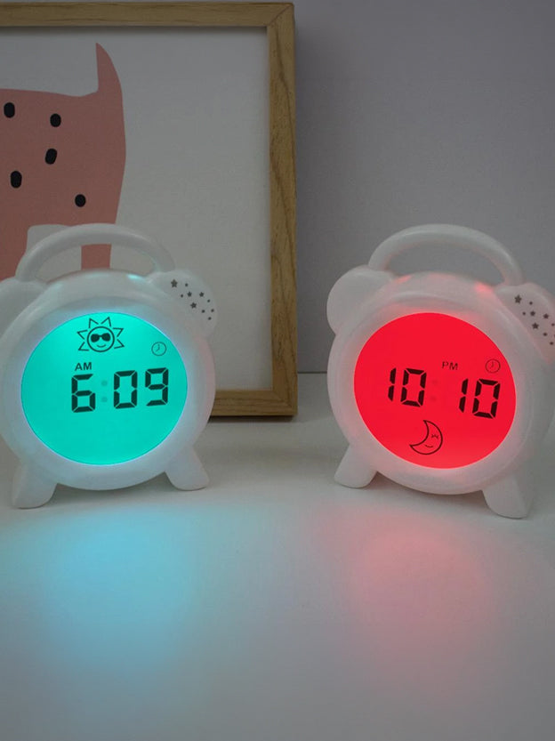 Two sleep trainer clocks one with a glowing green face, the other a red face for night time.