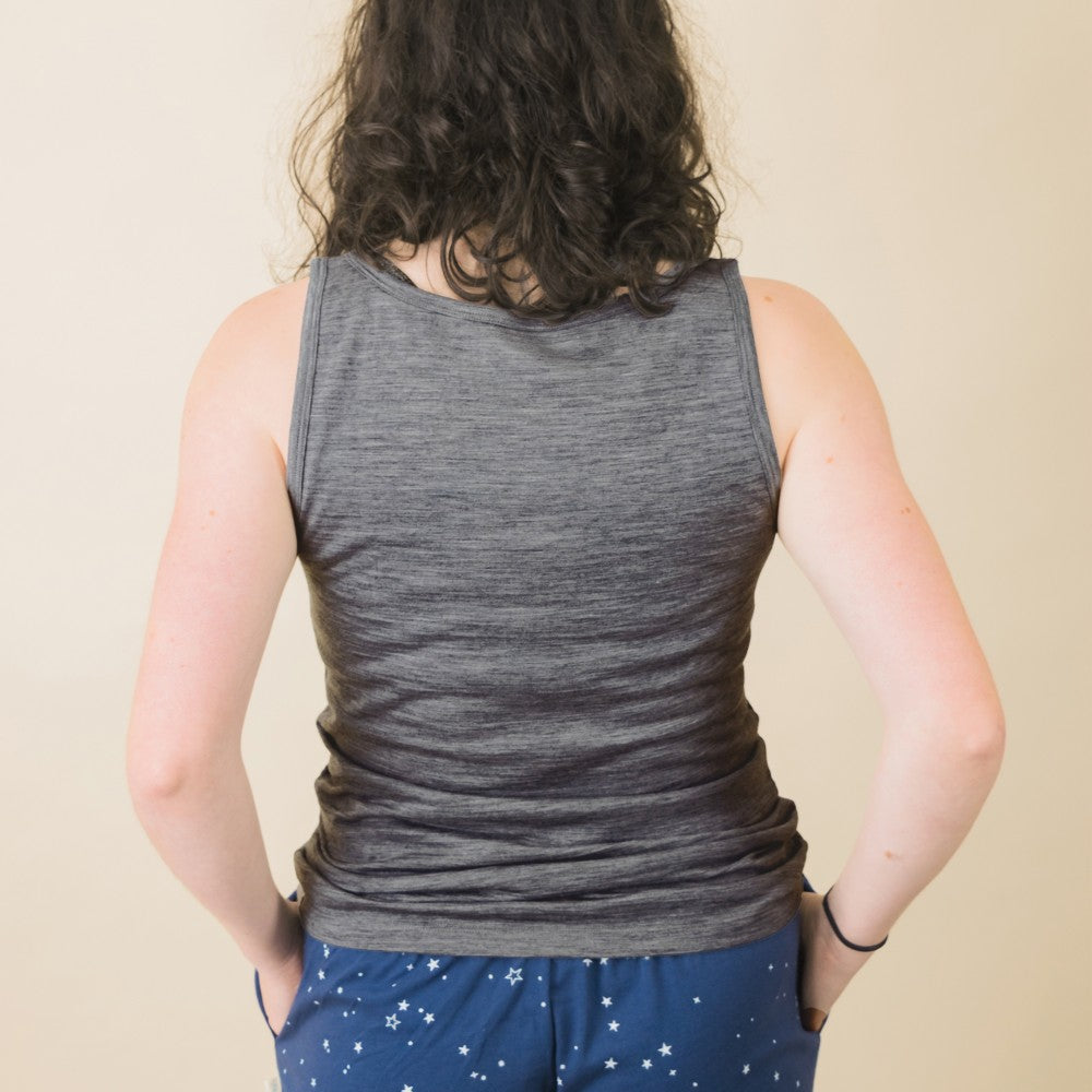 A person shown from the back wearing a gray sleeveless tank top and blue pants with a white star pattern, against a plain beige background.