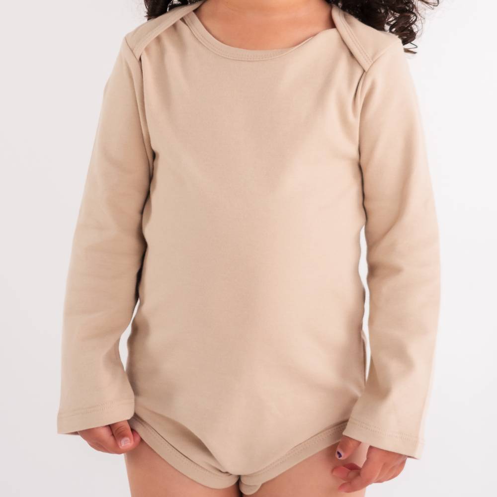 Close up of Beige long-sleeve bodysuit top worn by a child on a white background