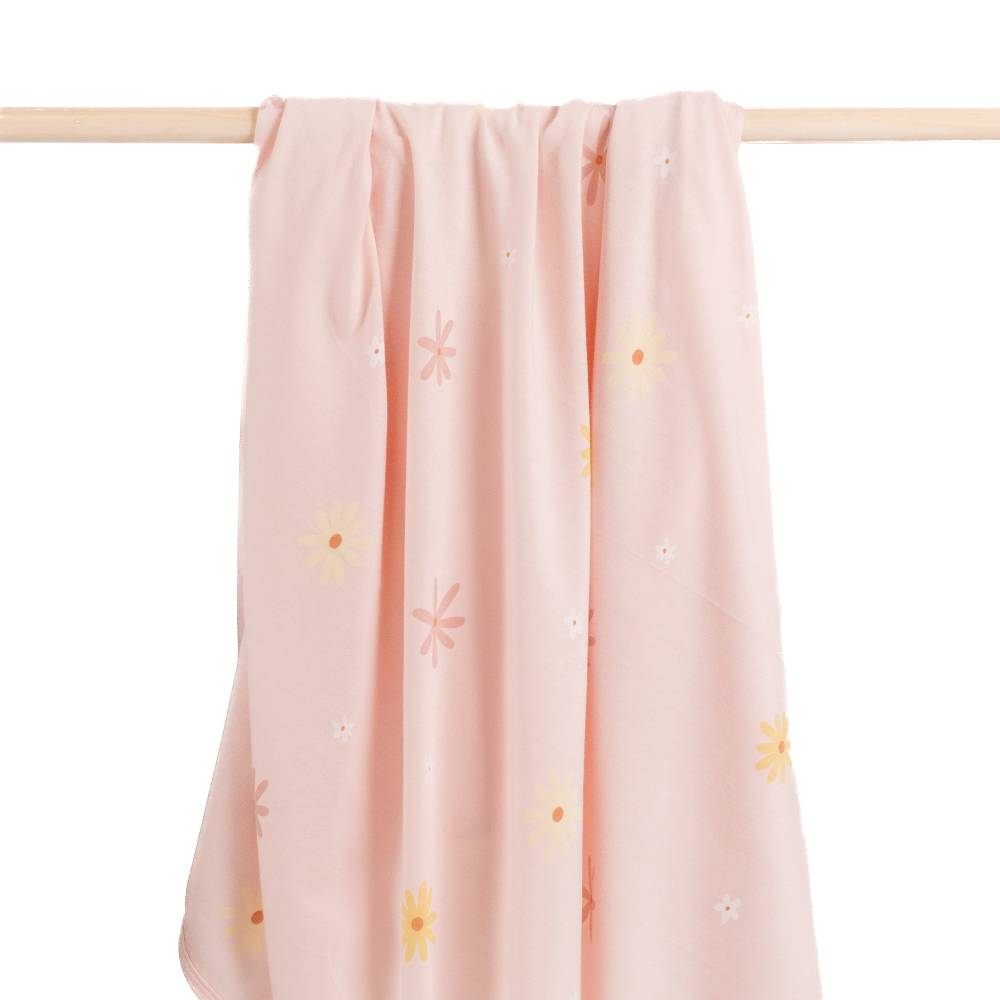 Pink swaddle blanket with floral patterns hanging on a wooden rod against a white background