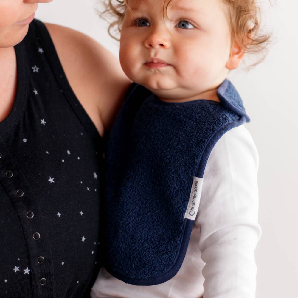 Baby wearing a navy blue bib held by an adult