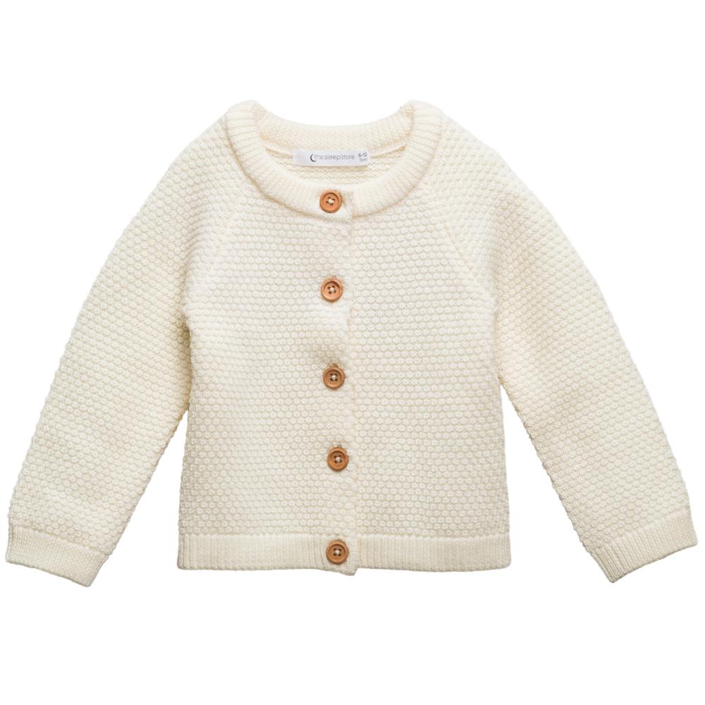 Cream-colored merino wool seed stitch knitted cardigan with brown buttons on a white background