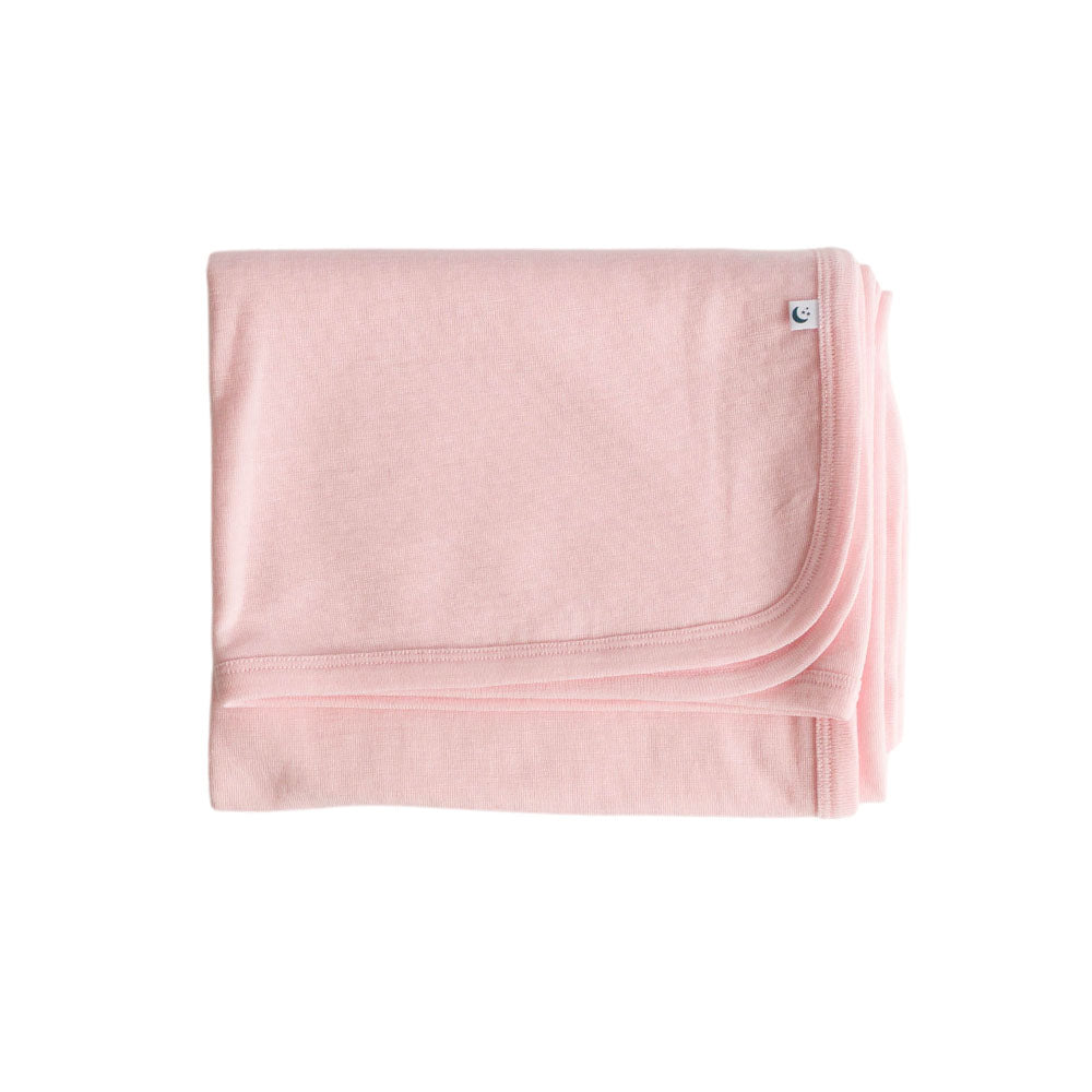 Pink deluxe rib merino wool blanket with a small 'The Sleep Store' brand logo on a white background