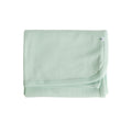 Folded light green deluxe merino rib blanket with a small The Sleep Store logo tag on a white background
