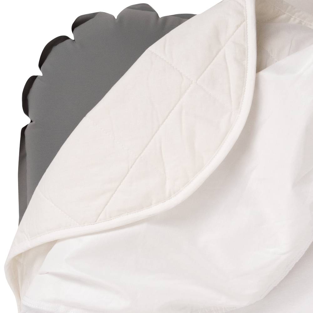 Close-up of a white quilted blanket with a gray blow up bed in the background