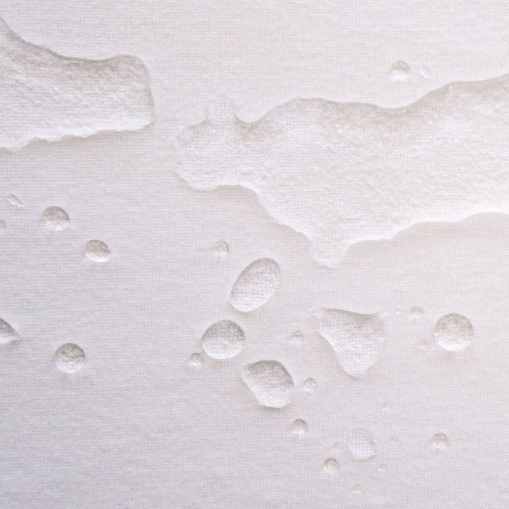 Close-up of water droplets on a textured white surface on a Folded white waterproof bedwetting protector sheet