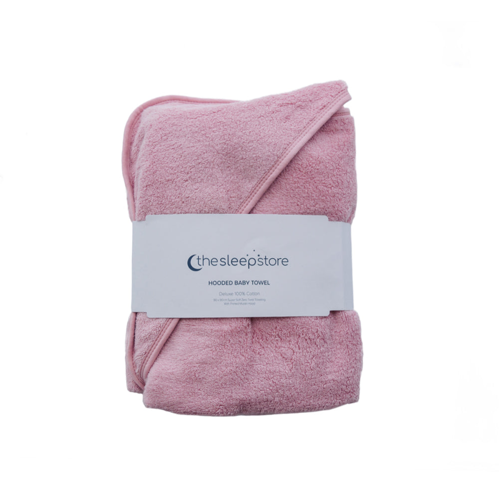 A folded dusty pink hooded baby towel with a white paper label band from 'thesleepstore' wrapped around it, set against a plain white background.