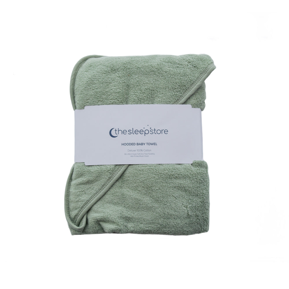 A folded terry cotton sage green hooded baby towel wrapped with a white paper label that reads 'thesleepstore'.