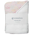 A folded hooded baby towel from thesleepstore, featuring a white plush terry cloth body and a hooded corner with a delicate pastel floral print in pink, yellow, and green. A white paper band with the brand logo is wrapped around the middle.