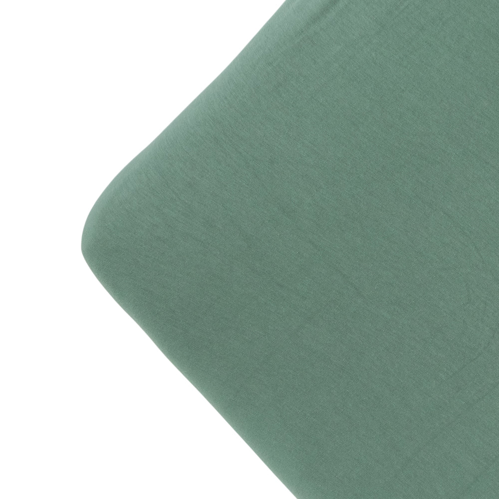 The corner of a mattress with a fern green colour fitted sheet, on a white background. 