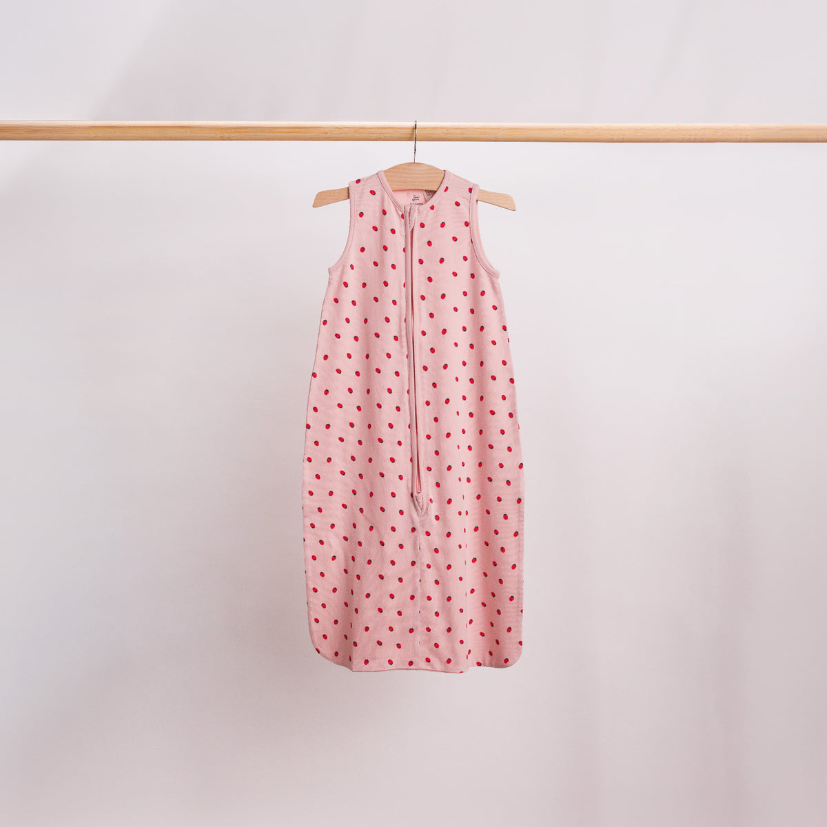 Hanging shot of a baby sleeping bag in the Blush Strawberries print. 