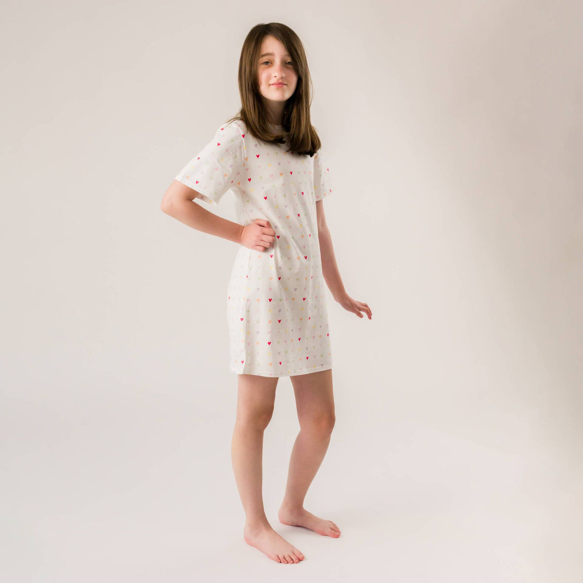 A young girl wearing a short sleeve summer nightie with a hearts print. 