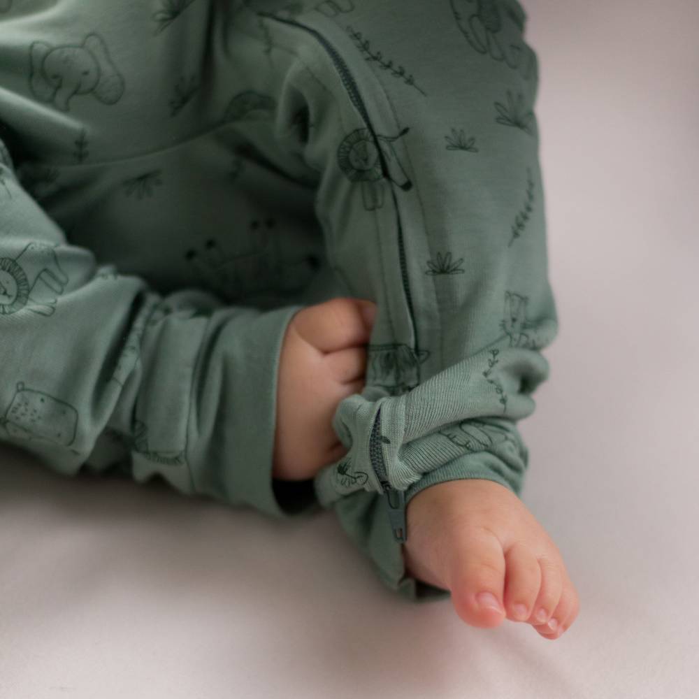 Close-up of a child's legs wearing a green patterned outfit on a light background