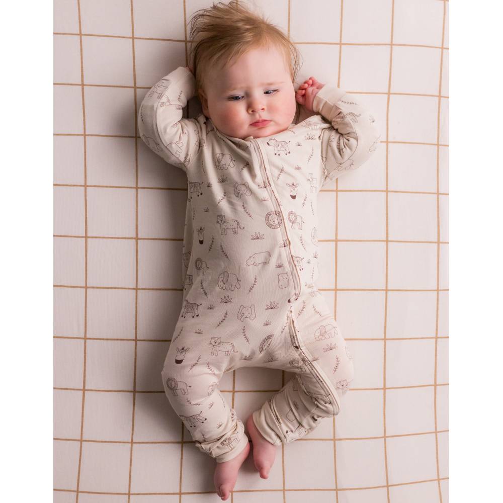 Baby lying in cot wearing a patterned onesie.