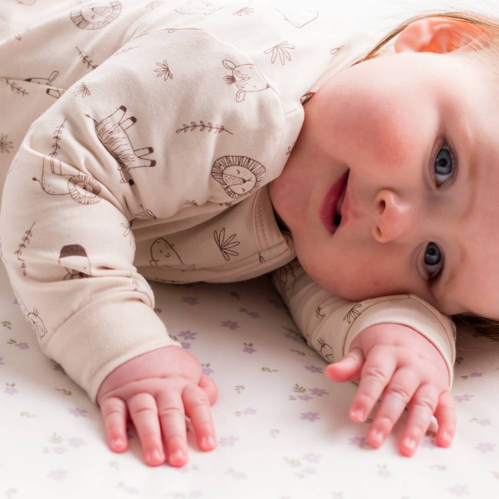 Baby lying on a white blanket with a patterned outfit