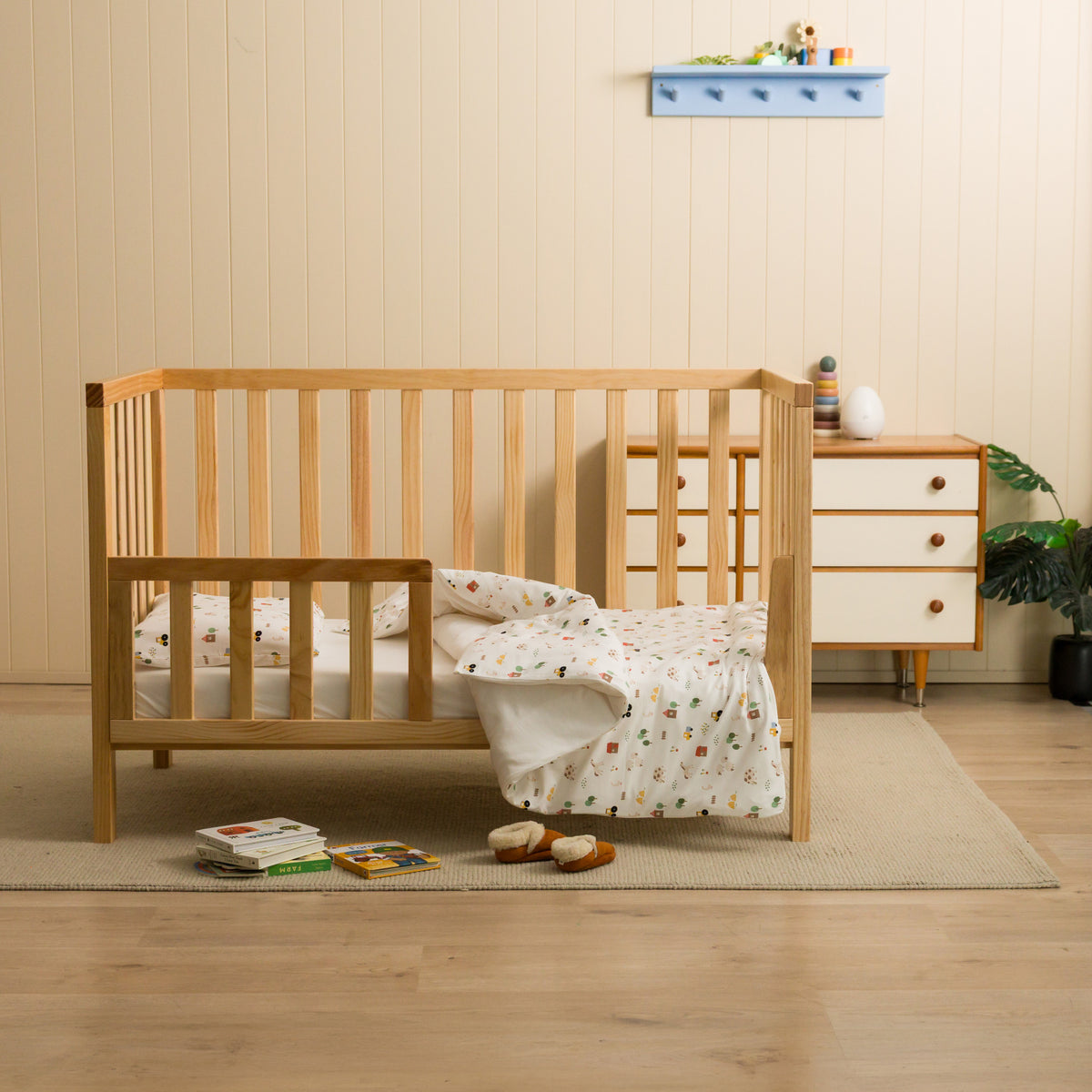 Nursery setting with a cot featuring a farmyard duvet cover. 