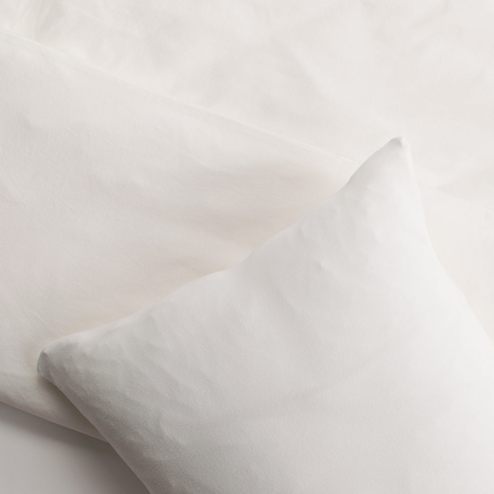 Close-up of a white or cream pillow and a light cream duvet cover 