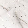 White jersey cotton fabric with small black and gold bee pattern shown as a duvet and pillowcase