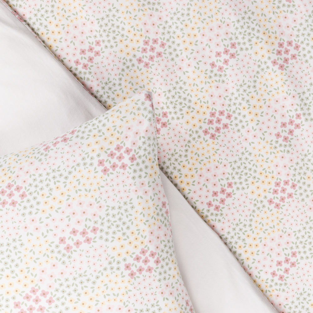 Cotton Floral patterned cot duvet and pilow with small pink and yellow flowers on a light background
