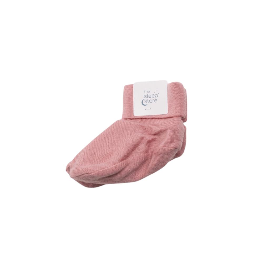 Pink merino baby bootie with a white label on a white background