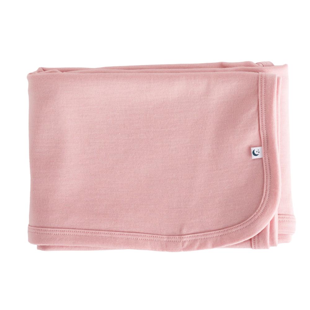 Folded pink merino baby blanket with a small logo on a white background