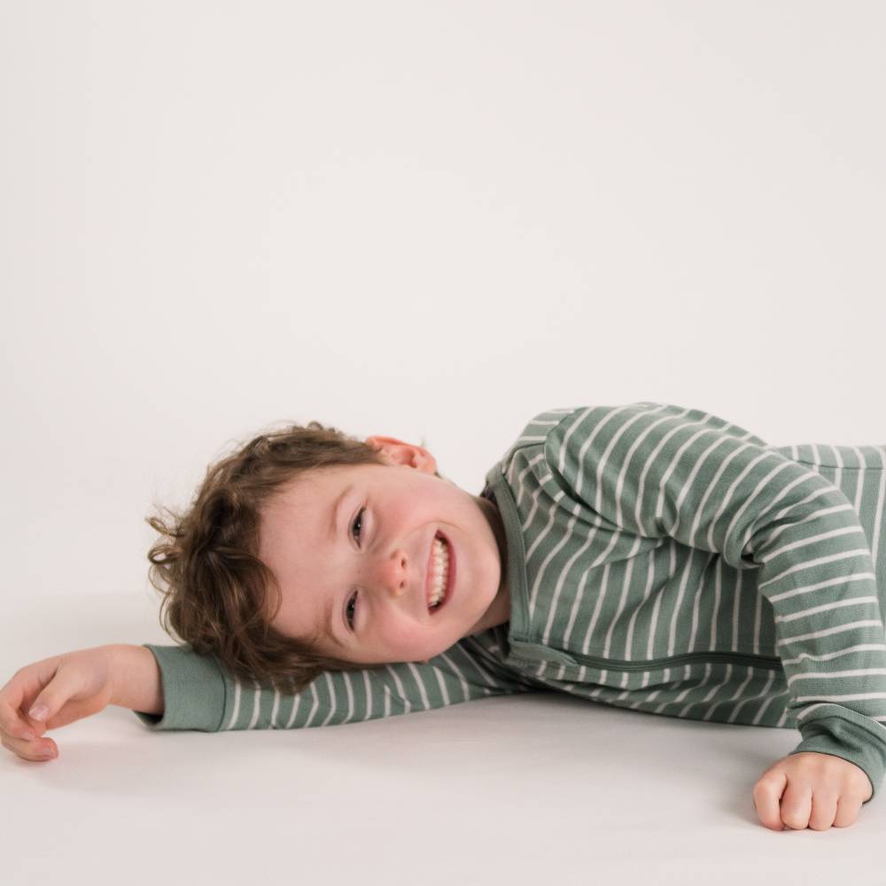 Child wearing a merino striped shirt on a plain background