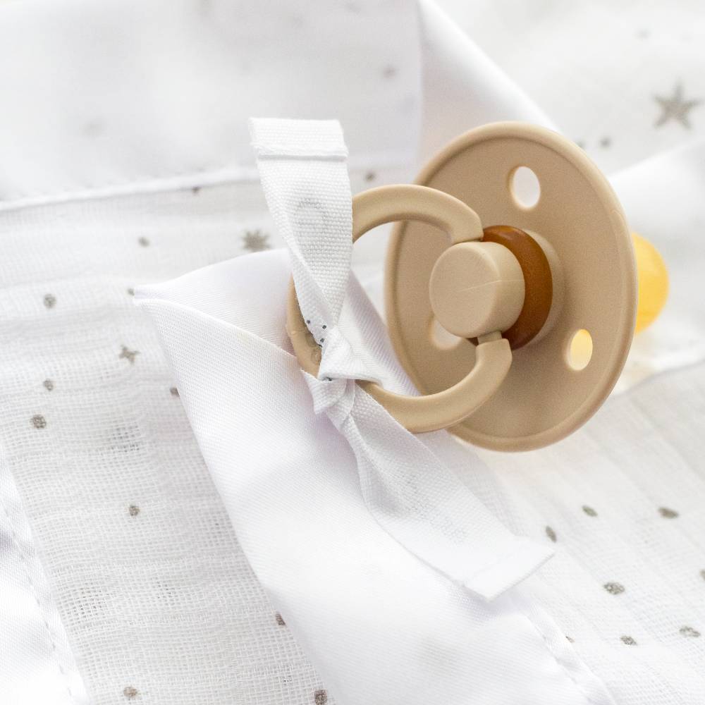 Pacifier attached to cotton muslin comforter