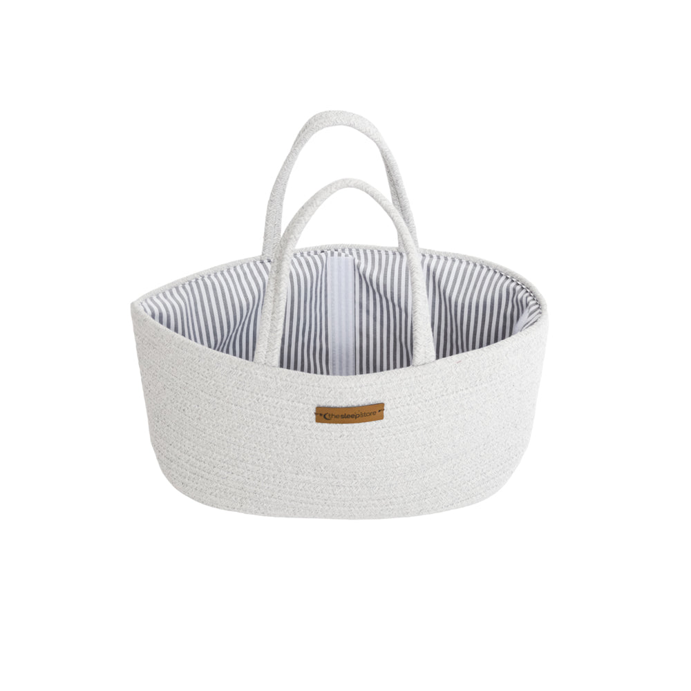 A light gray woven basket with two top handles and a striped interior, featuring a small brown leather brand patch on the front.