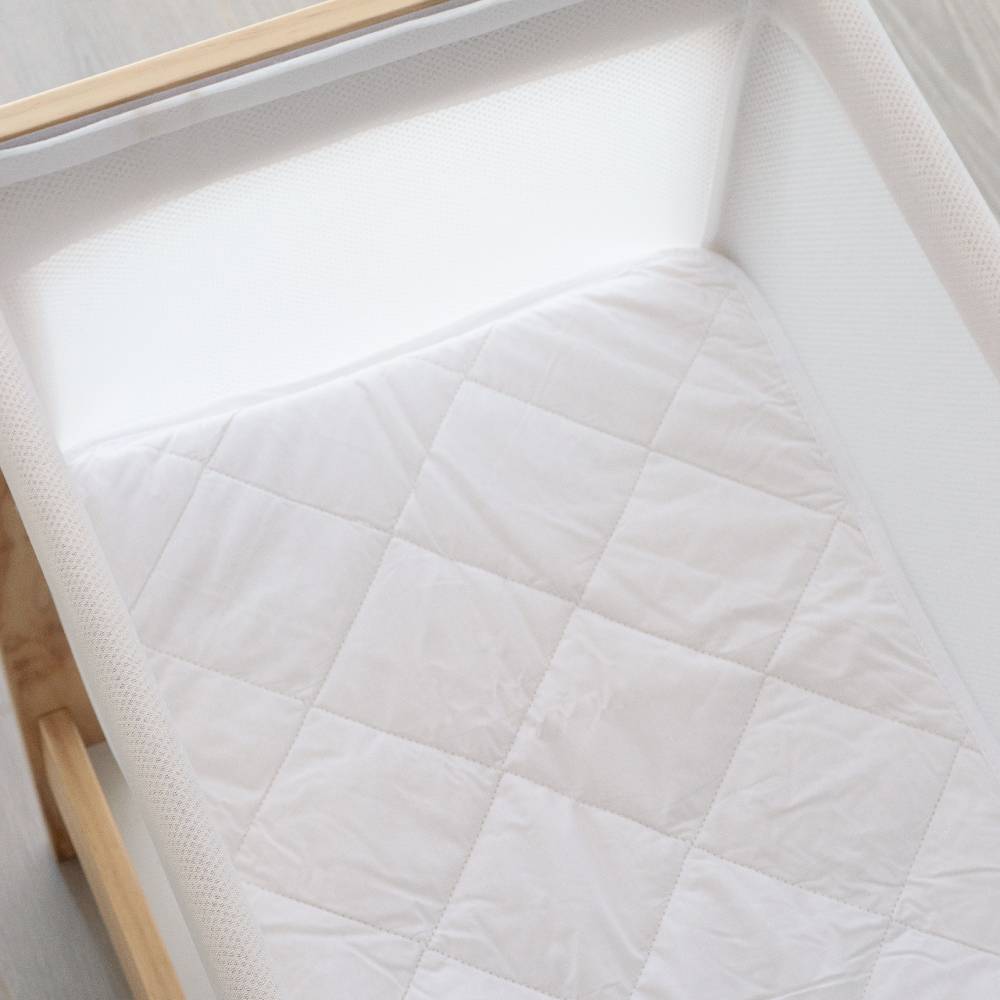 White quilted mattress cover on a wooden bed frame