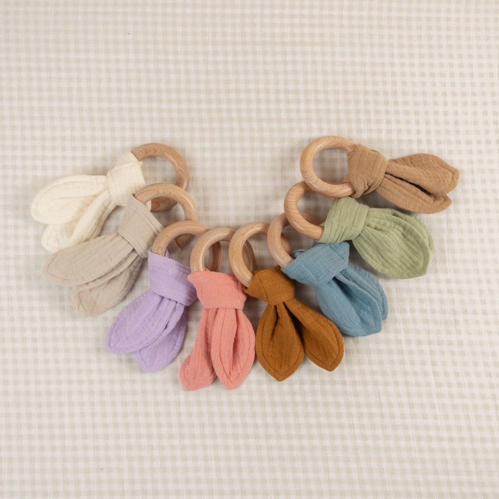 Set of colorful wooden teething rings on a textured beige background
